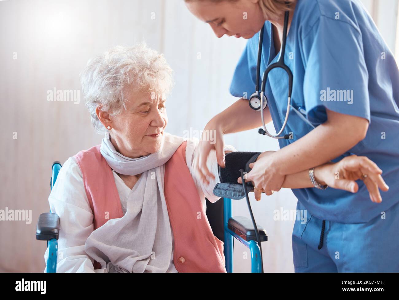 Disability, monitor and old woman with a nurse for blood pressure check in a medical healthcare hospital. Wheelchair, doctor and caregiver helping a Stock Photo