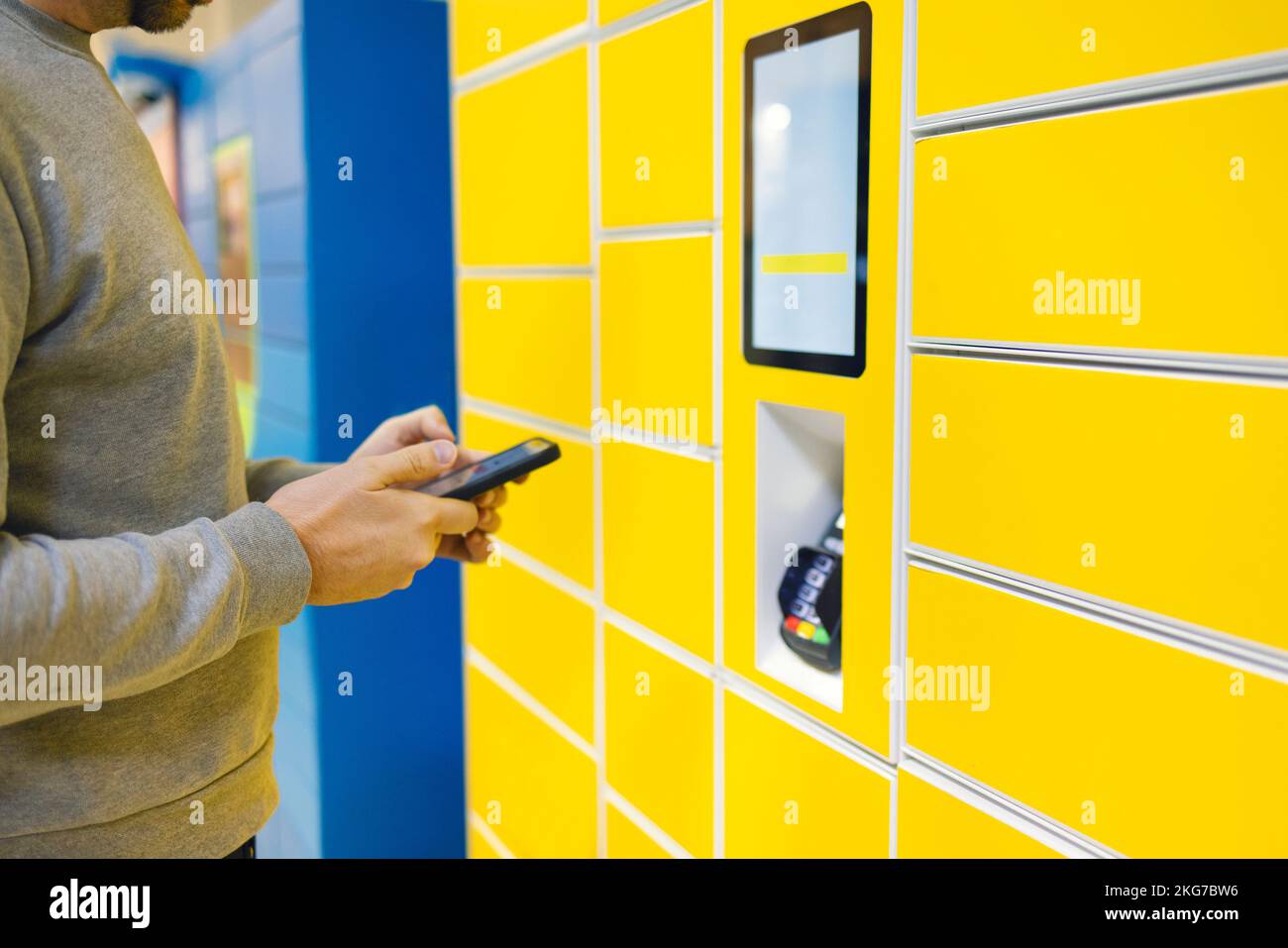 Close up of a man picks up mail from automated self-service post terminal machine. Parcel shipping service or delivery packaging concept Stock Photo