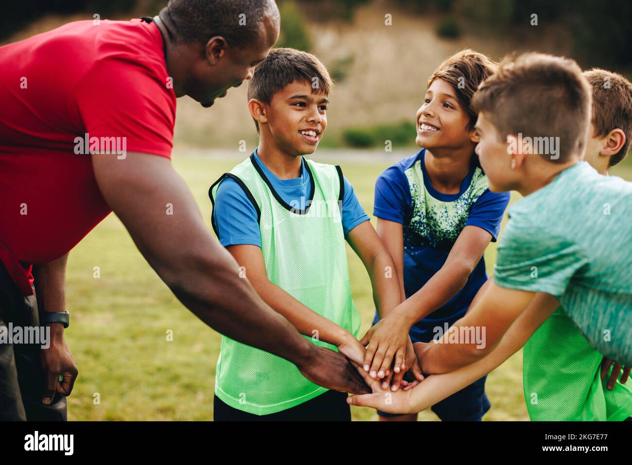 Sports trainer having a huddle with his team in a school field. Rugby coach giving his students a motivational talk before practice. Sports mentorship Stock Photo