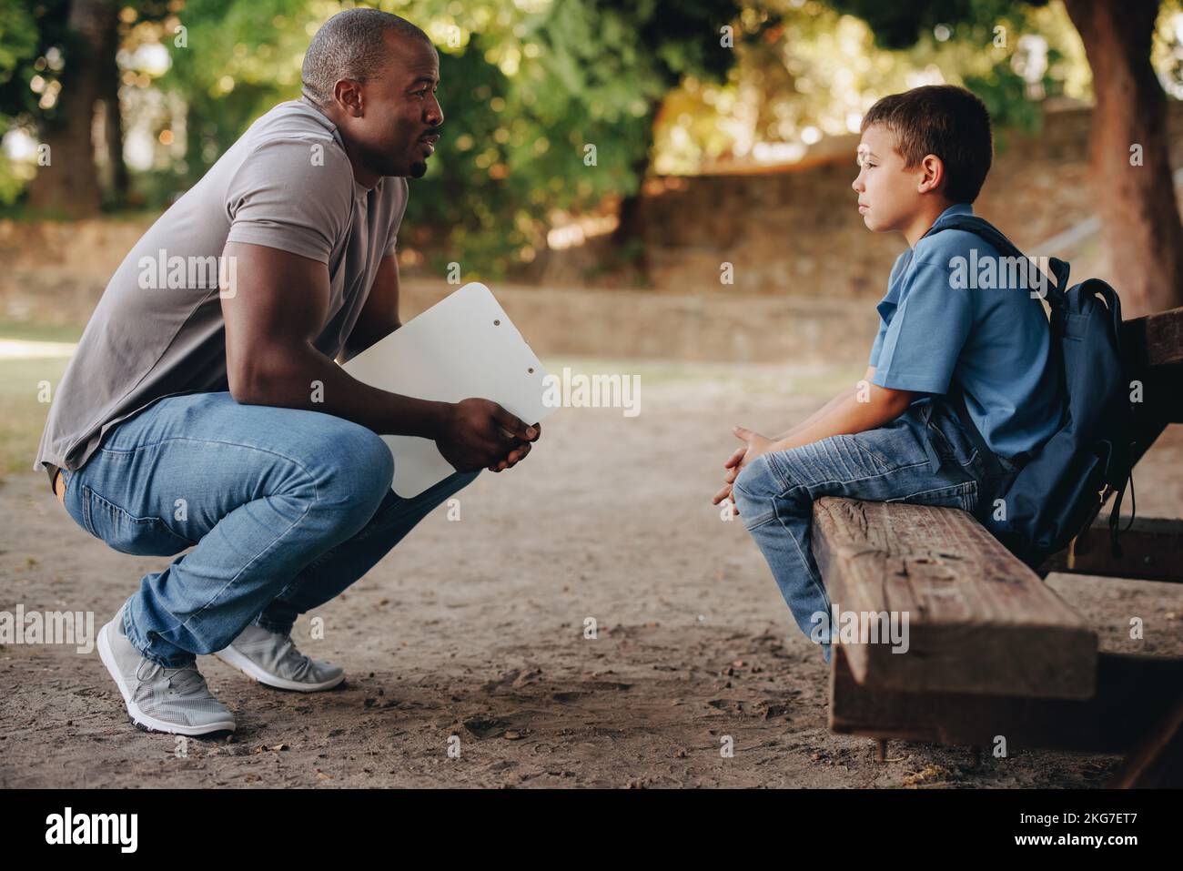 School teacher motivating a young primary school kid outside class. Child mentor talking to a troubled school boy. Support and encouragement for a stu Stock Photo