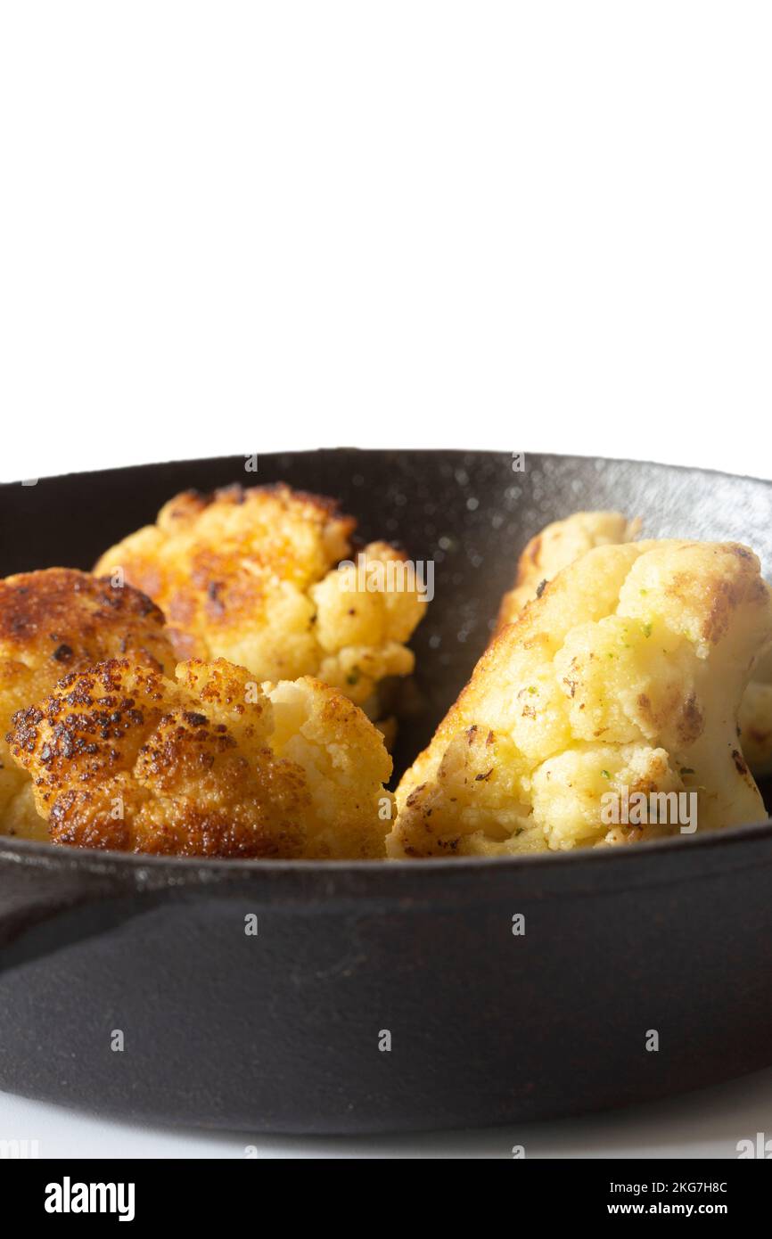 Cauliflower fried, in a cast iron frying pan with olive oil. Isolated on a white background Stock Photo