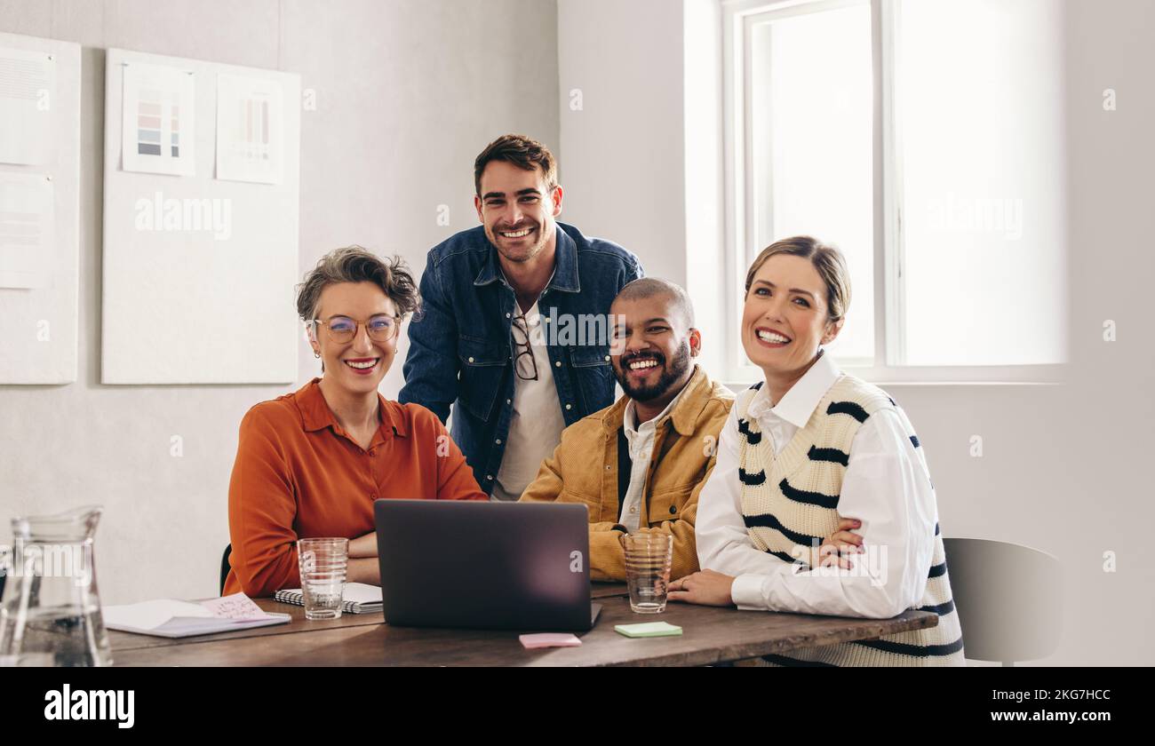 Portrait of successful businesspeople smiling at the camera in a creative office. Group of happy businesspeople working together on a new design proje Stock Photo