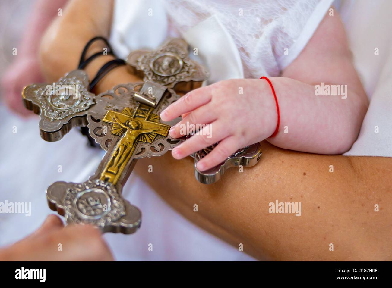 Christian baby hands over a priest's golden silver cross in a church. Child baptism christening. High quality photo Stock Photo