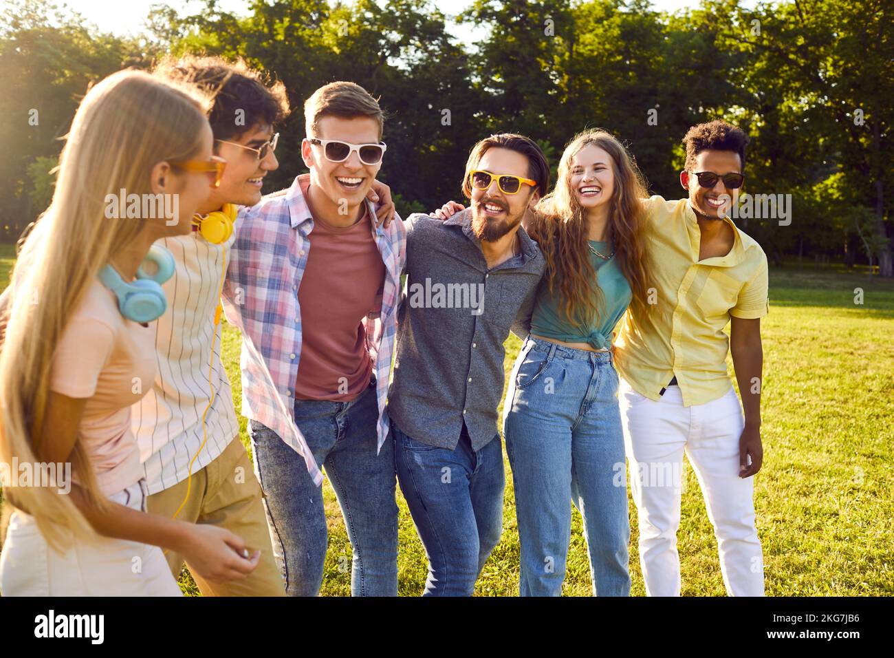Young happy multiracial people men and woman walk around summer park together with friends Stock Photo