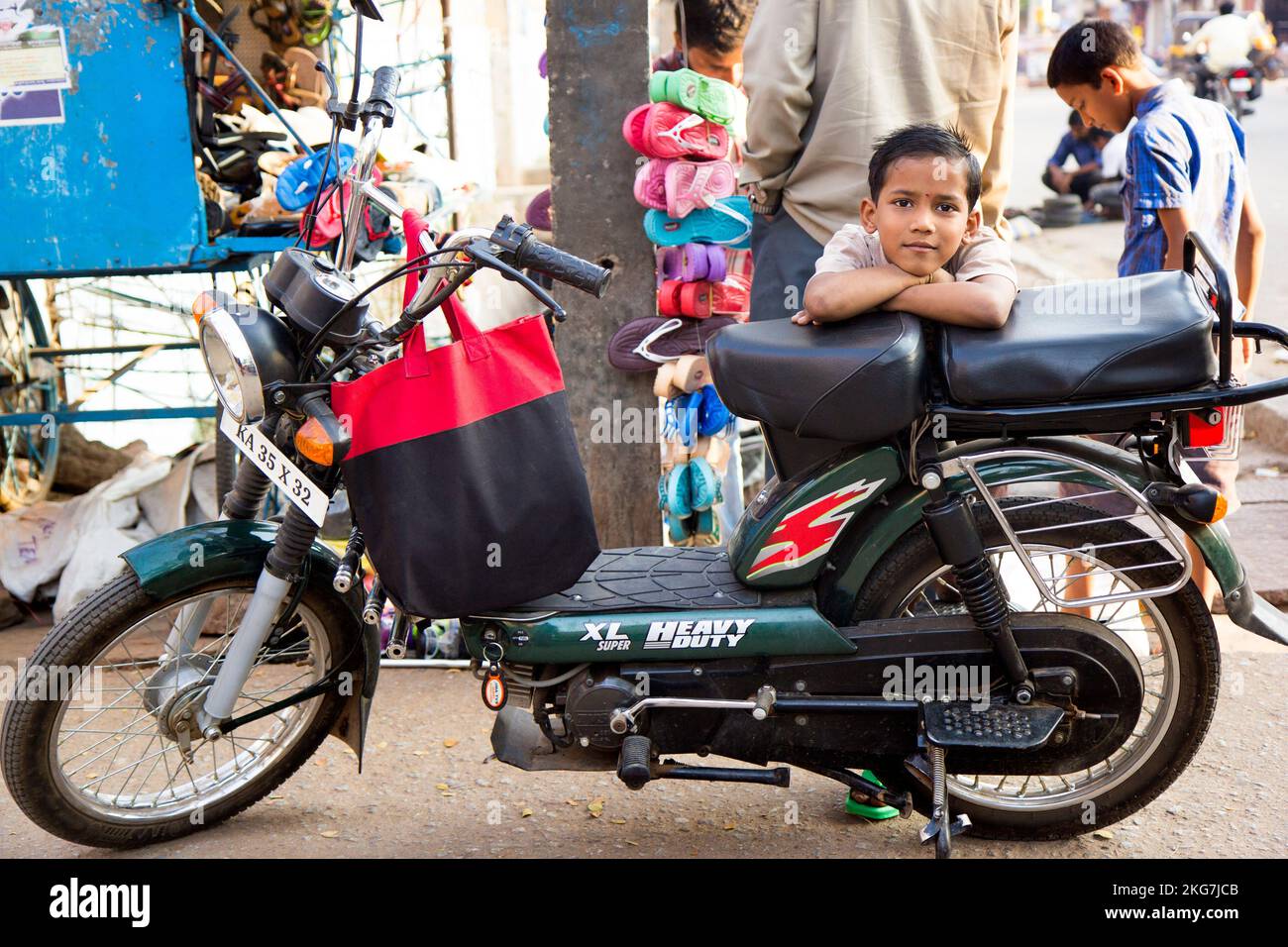 A Cute Indian kid boy leaning on a motorbike in the street Stock Photo ...