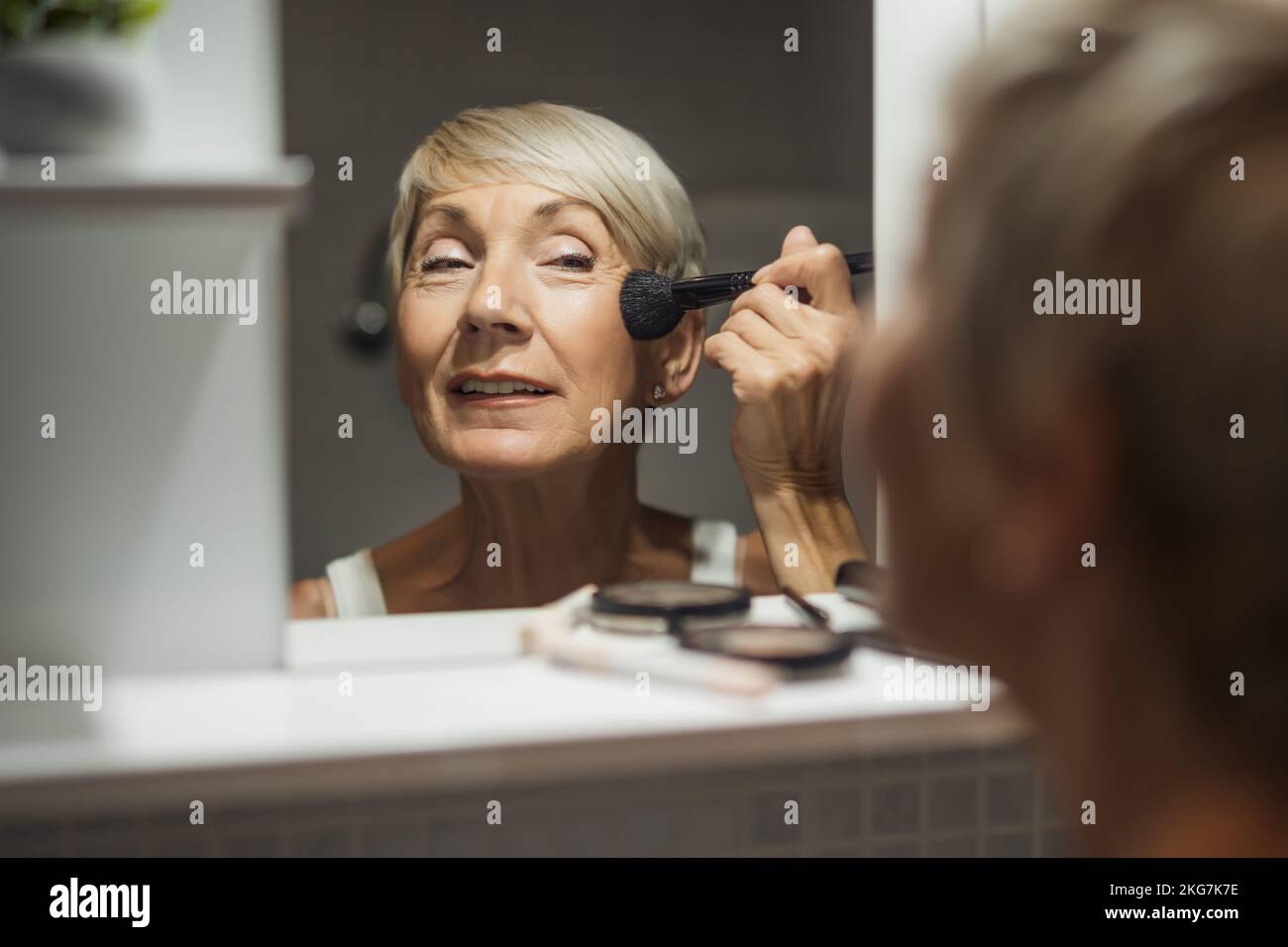 Mature woman is applying blush in the bathroom Stock Photo Alamy