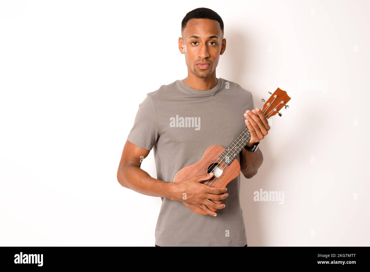 Young handsome african american man plays ukulele isolate over white background, Stock Photo