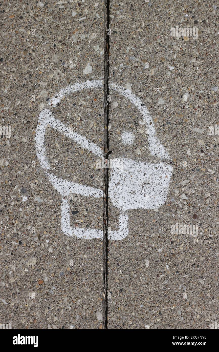 The standard masked face symbol spray painted on the sidewalk for