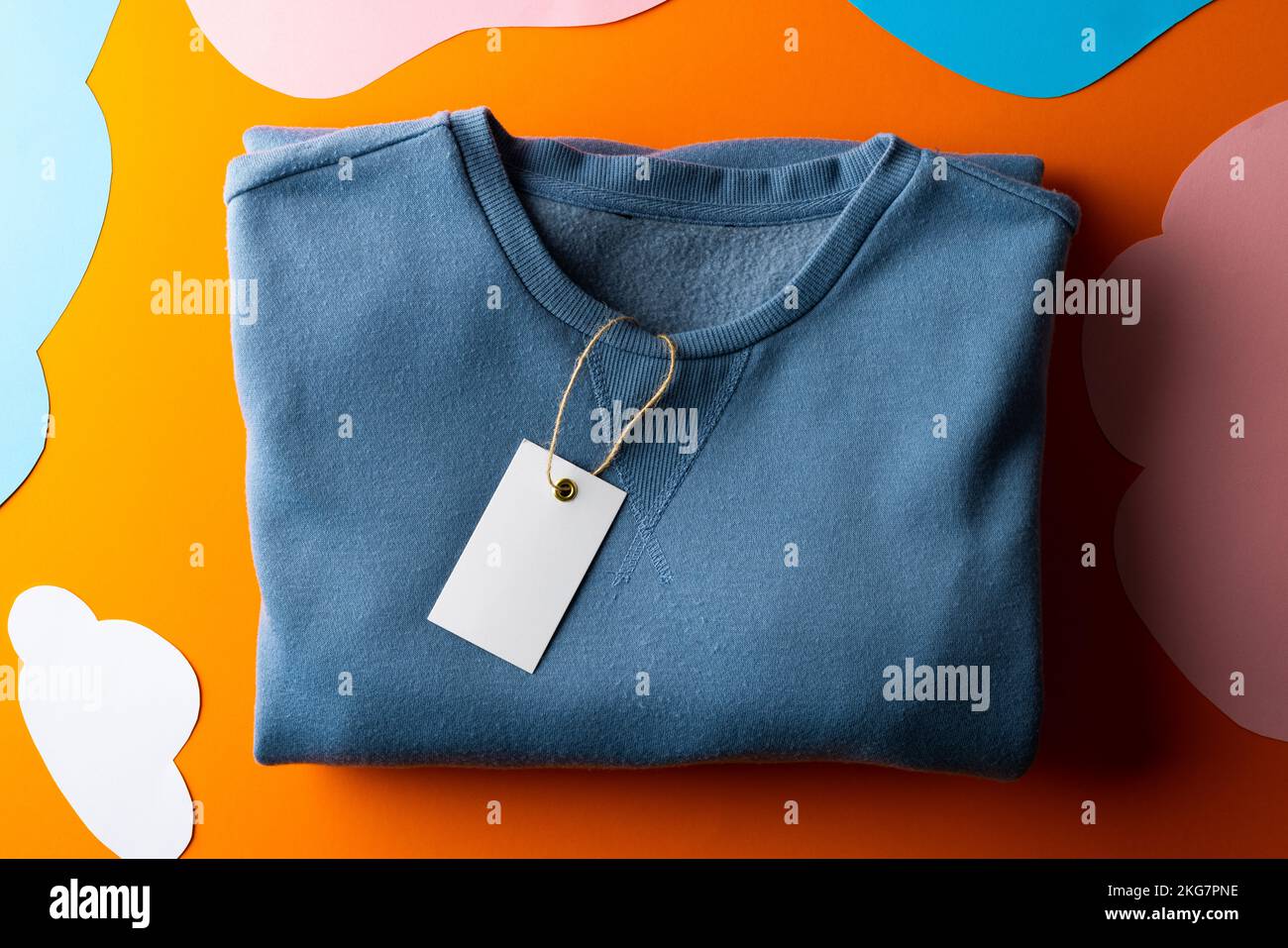 Close up of sweatshirt with tag and copy space on orange background Stock Photo