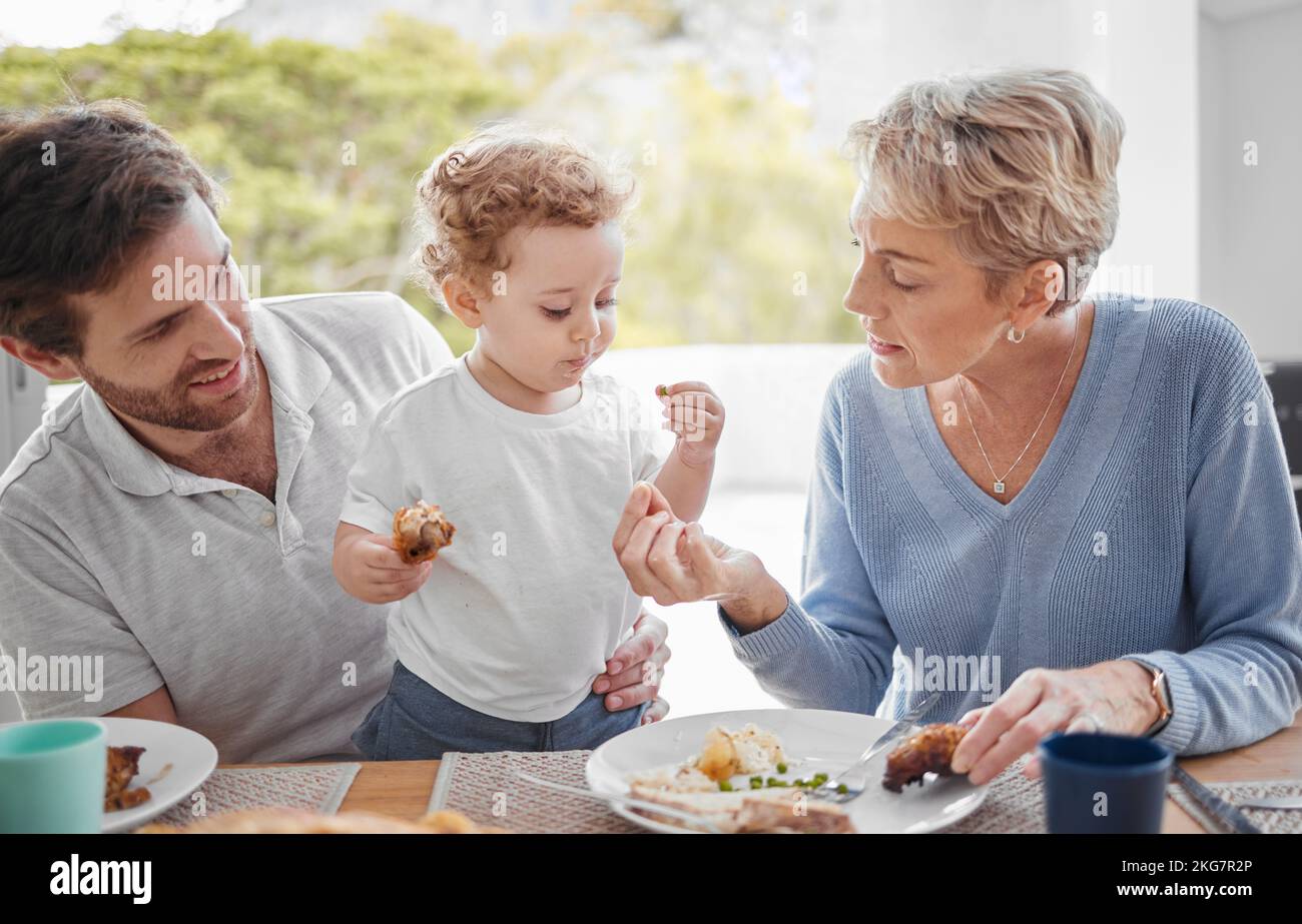 Family, food and eating with baby while feeding healthy diet or nutrition in the family lunch in home. Grandmother, child and dad with hungry boy kid Stock Photo