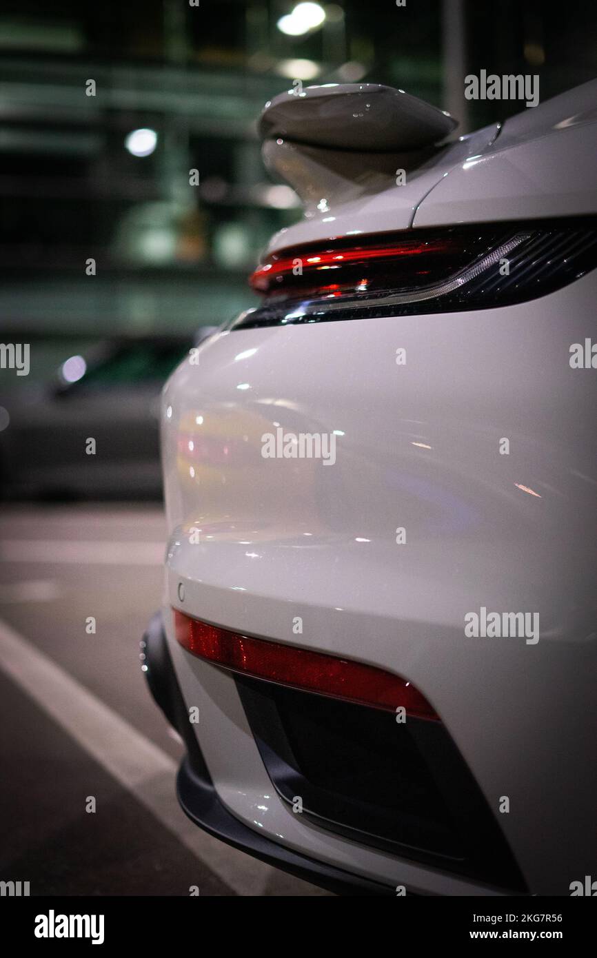 A closeup of a grey Porsche car rear with the spoiler at a parking spot. Stock Photo