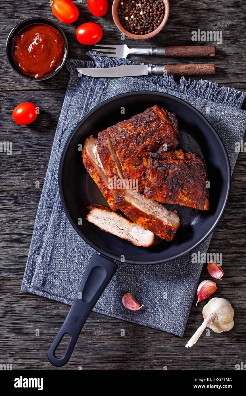 roast baby back pork meaty ribs in a pan on dark wooden table with