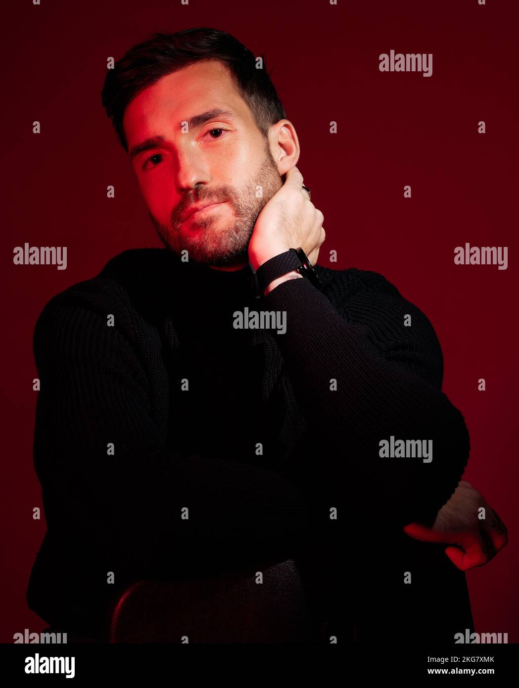 Fashion, man and neon light for aesthetic model in studio for beauty, success and art portrait on red background. Handsome male in black clothes for Stock Photo