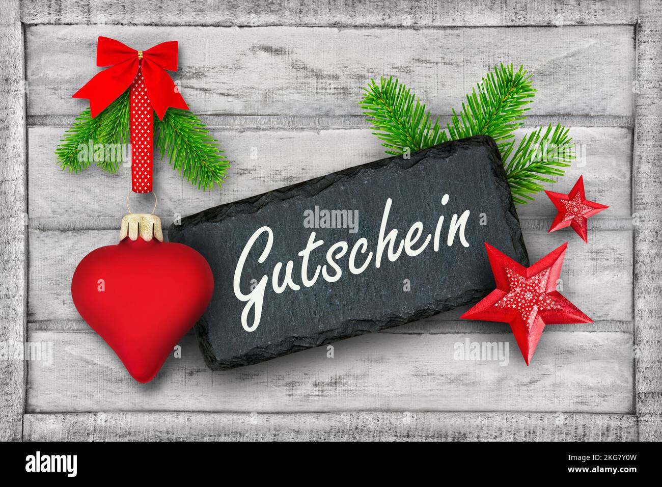 Gutschein für Weihnachten und rote Dekoration mit Herz, Tannenzweigen und Label auf Holz Stock Photo