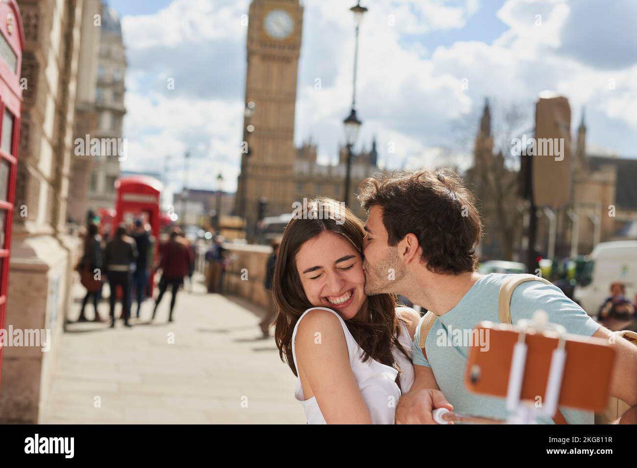 Couple, travel and selfie with kiss outdoor in London for romantic holiday, adventure and love in city street. Man, woman and smartphone, happiness Stock Photo
