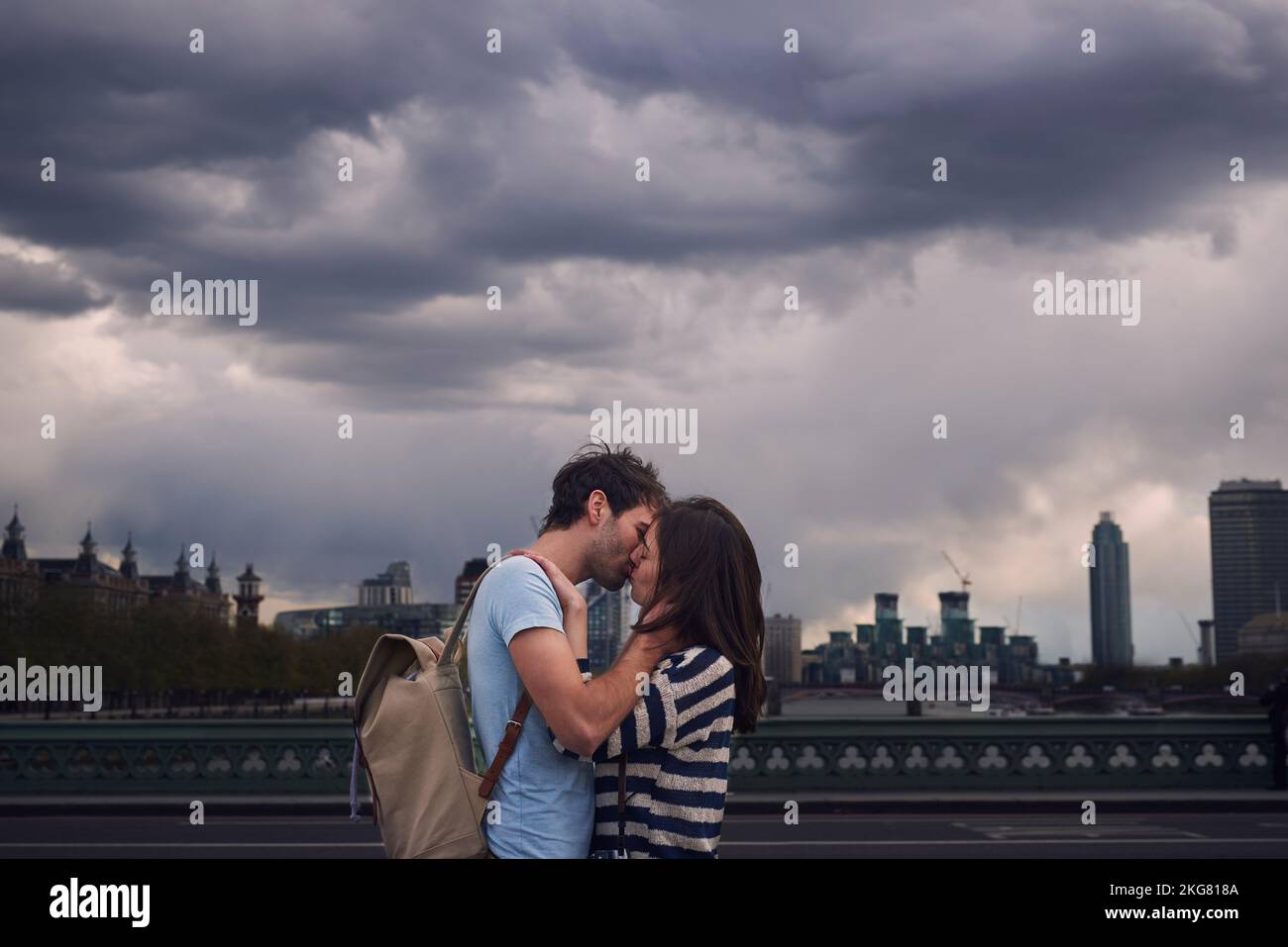 Love, couple and kiss on city bridge or outdoors in town on vacation, trip or holiday, Cloudy day, romance and affection of man and woman kissing in Stock Photo