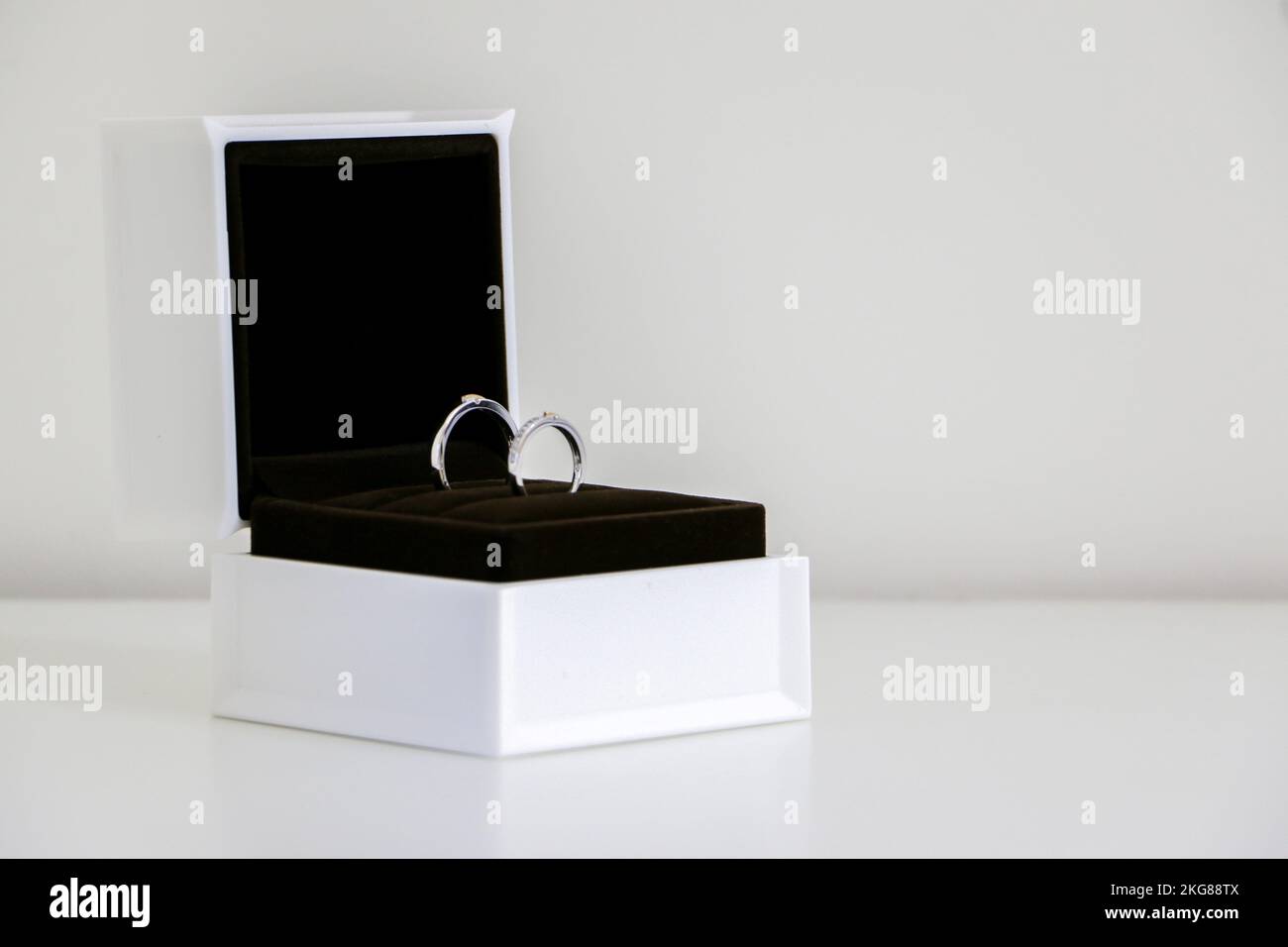 A pair of beautiful shiny wedding rings sparkling in open ring box left side, isolated against white background, symbol of romance, love and marriage. Stock Photo