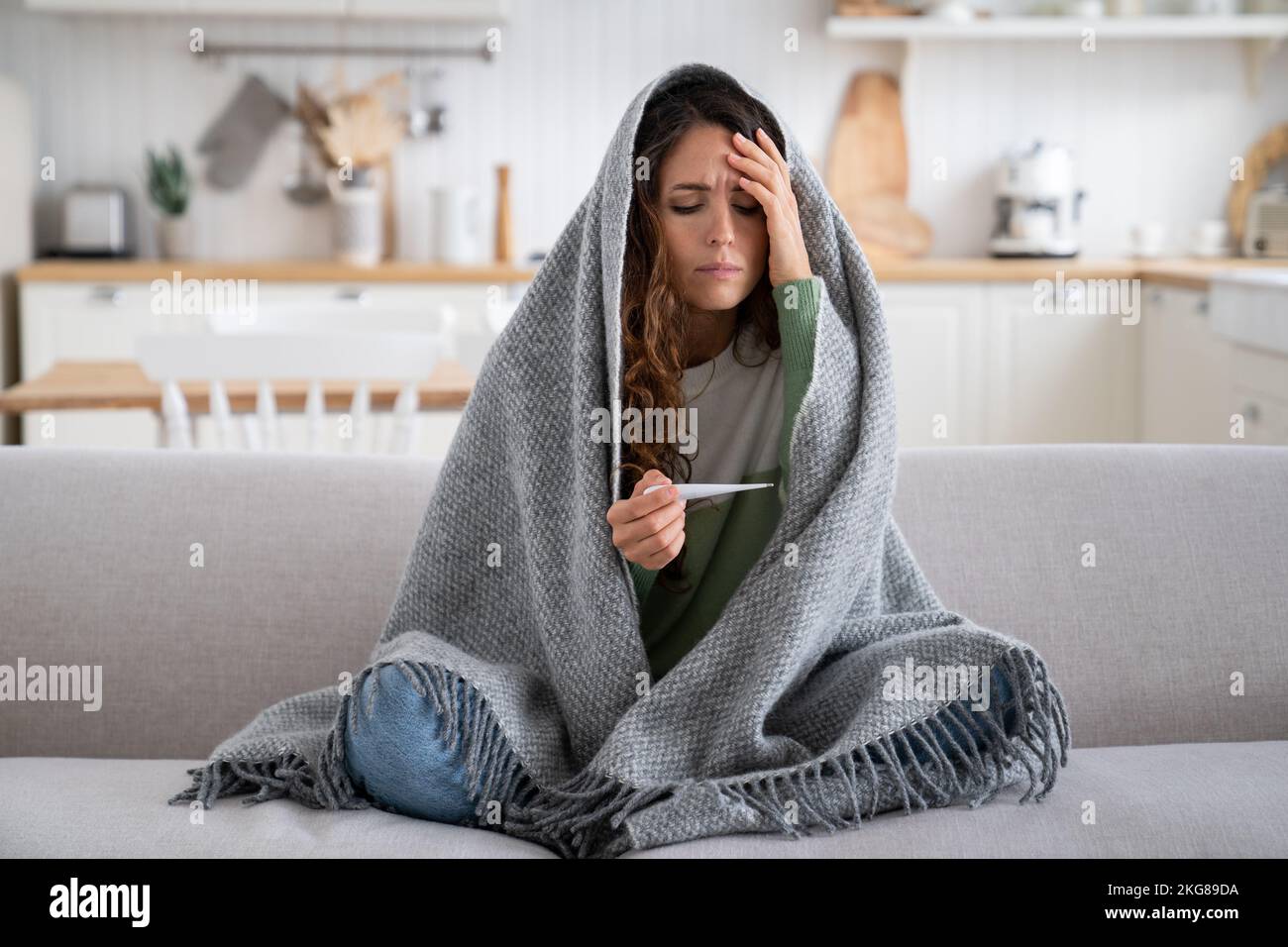 Sick exhausted woman with thermometer to measure body temperature sit