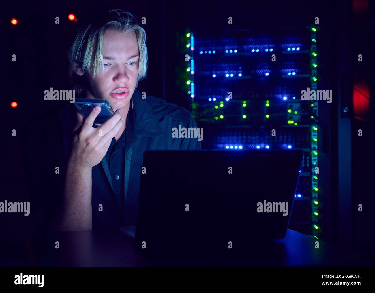 Technician using laptop and smart phone in server room Stock Photo