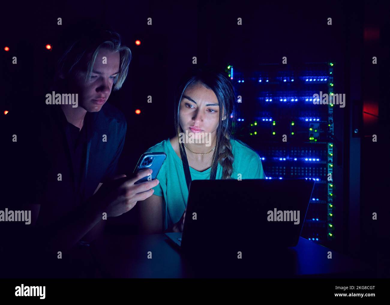 Technicians using laptop and smart phone in server room Stock Photo Alamy