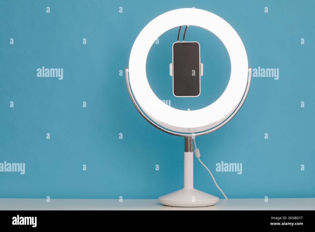 Ring light and smart phone on blue background Stock Photo