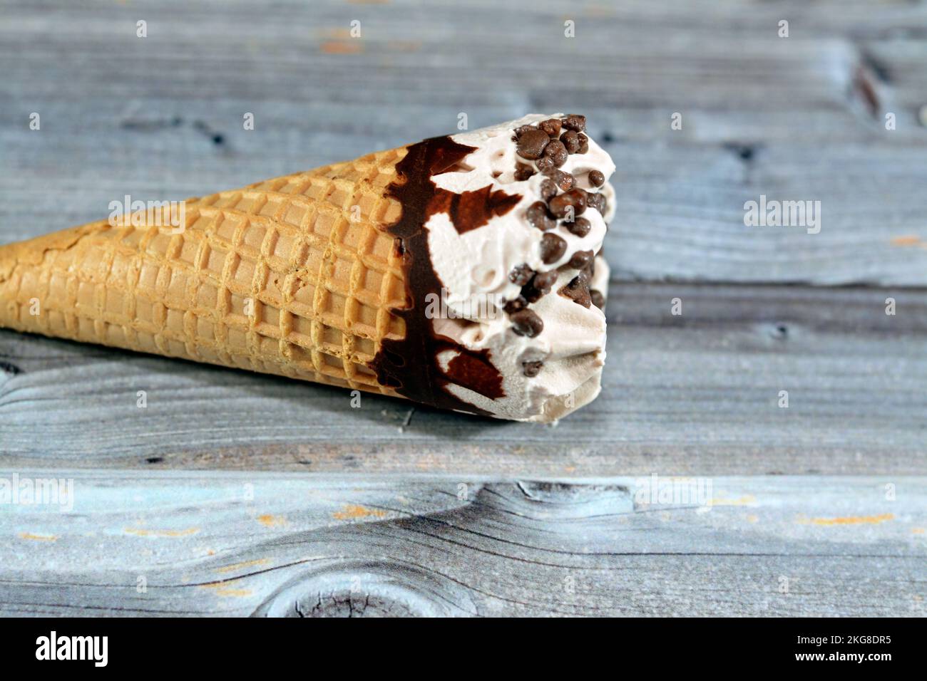 Ice cream vanilla cone with topping of chocolate chips pieces in a