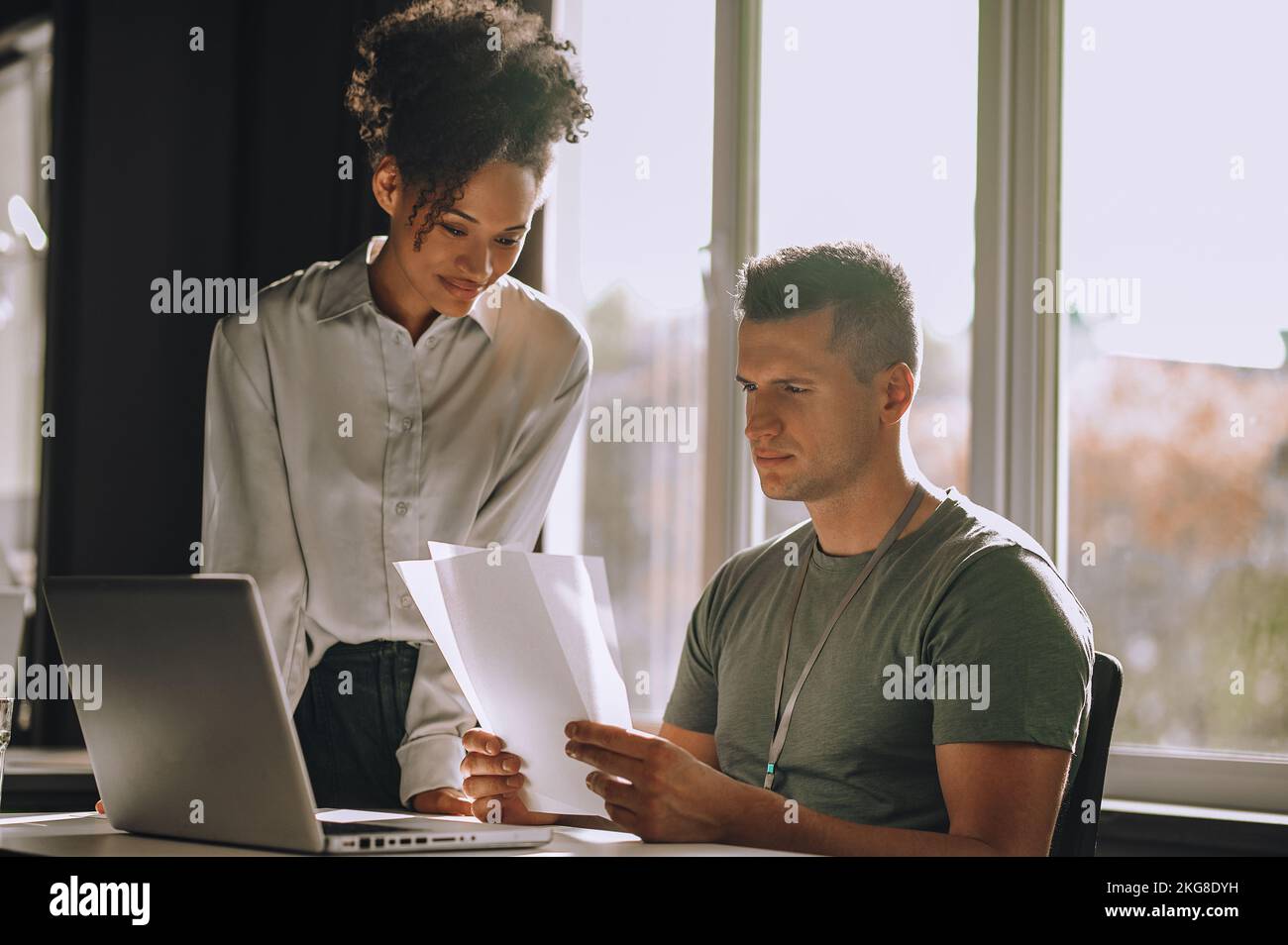 Pleased female assistant looking at documents in her boss hands Stock Photo