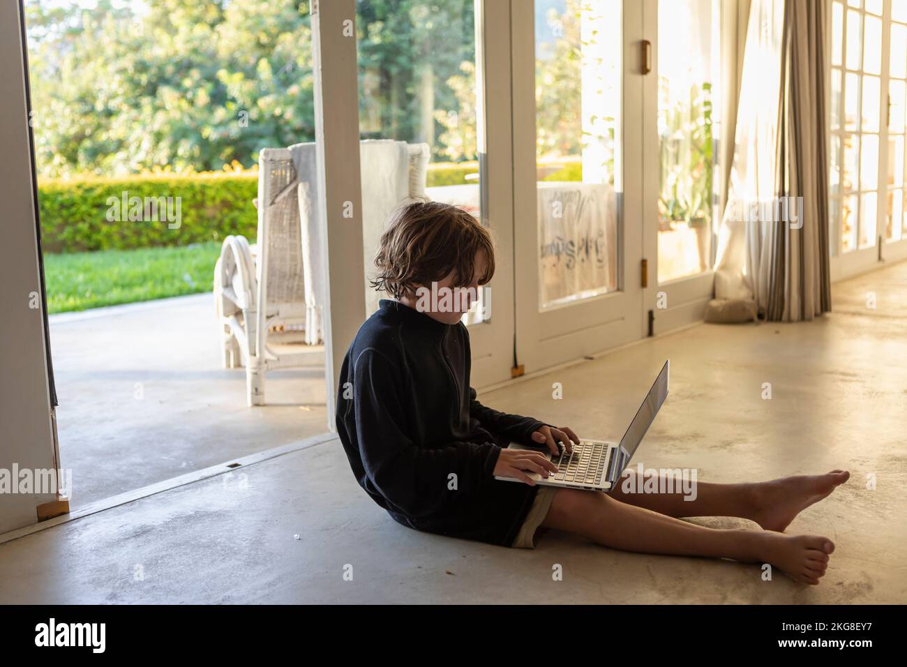 Boy (8-9) using laptop while sitting on floor Stock Photo