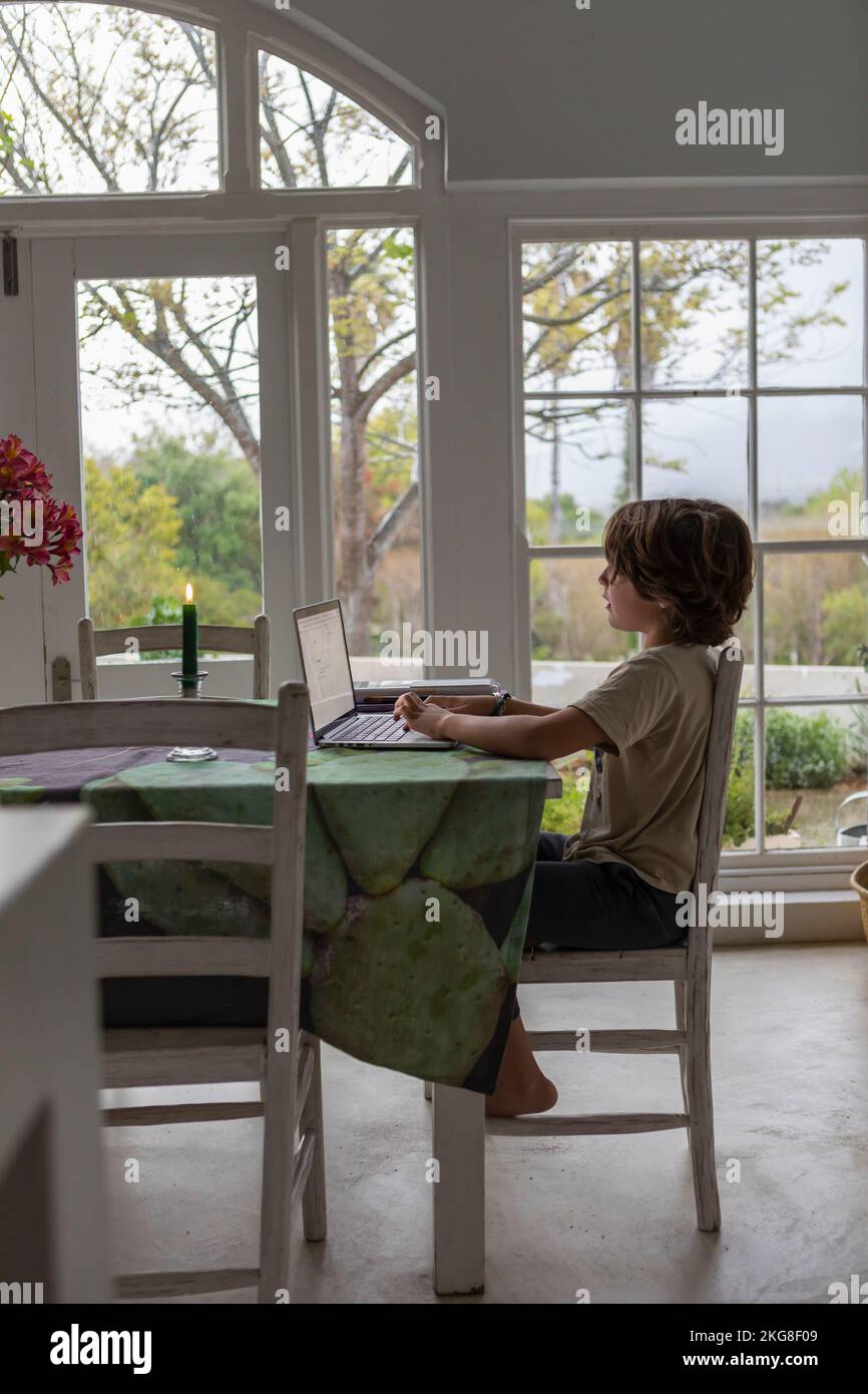 Boy (8-9) using laptop in dining room Stock Photo