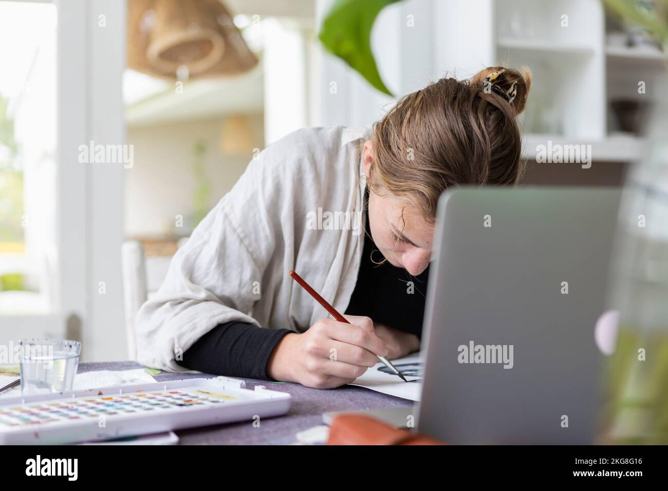 Teenage girl (16-17) artist working in art studio doing a watercolor ...