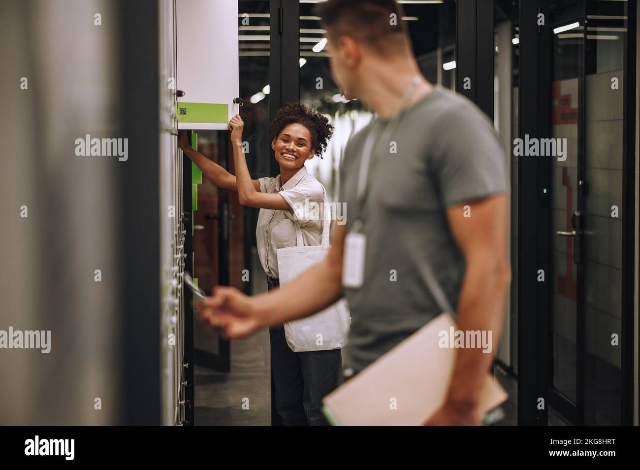 Joyful office worker and her coworker opening section lockers Stock Photo