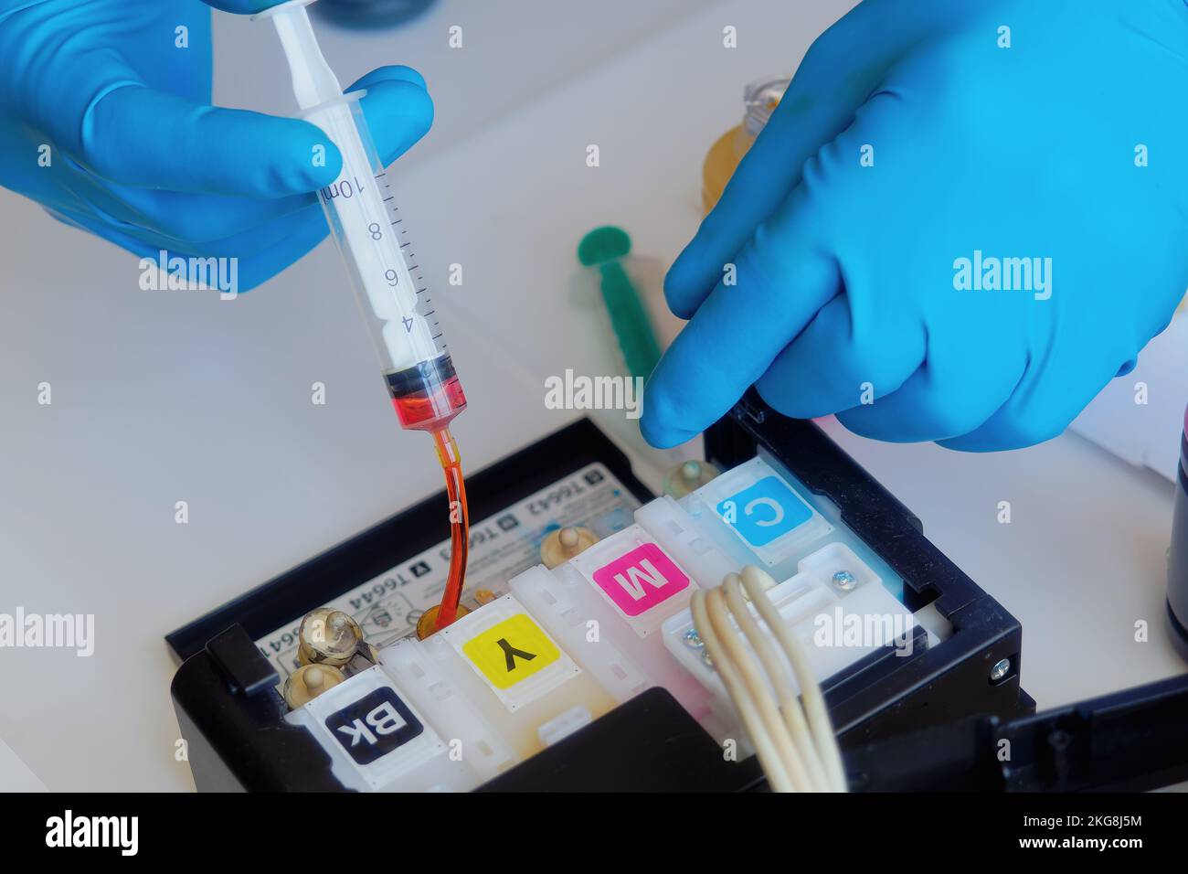Printer maintenance. Master fills inkjet printer with ink or syringe paint. Hands with gloves close-up.. Stock Photo