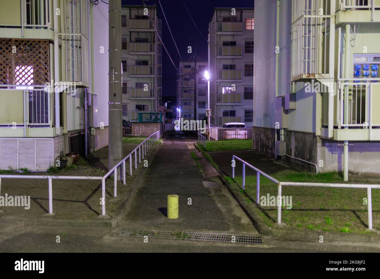 Dark walkway through multi-story apartment buildings at night Stock Photo