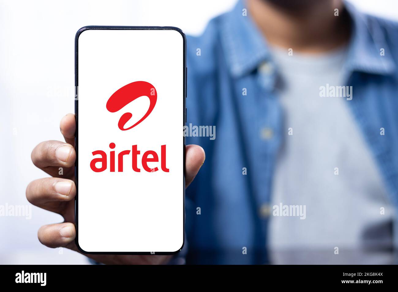 Close up of a smart phone screen with airtel logo held in hand by an Indian male Stock Photo