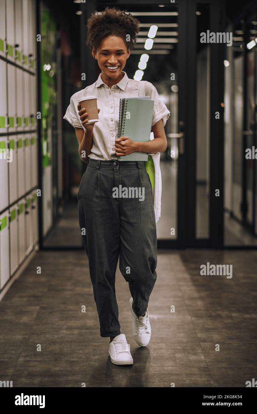 Joyous employee standing in the corridor during the coffee break Stock Photo