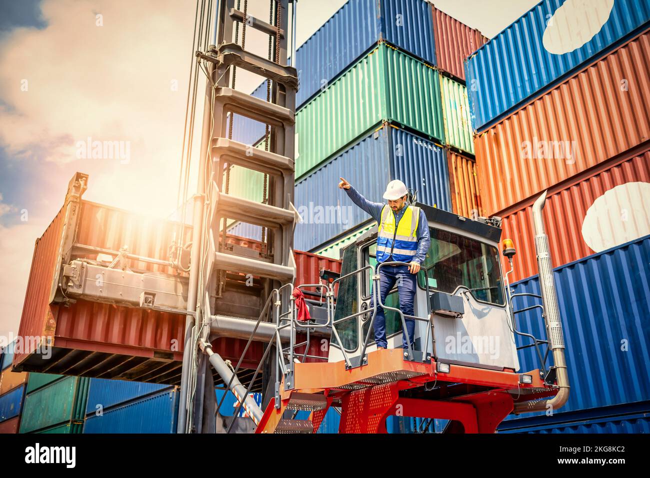 Handsome Engineer or foreman wears PPE checking container storage with cargo container background at sunset. Logistics global import or export shippin Stock Photo