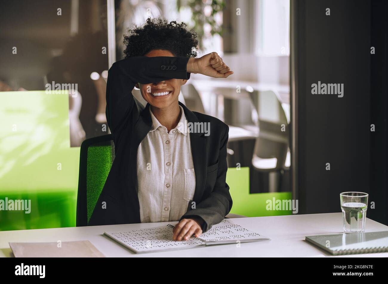 Visually impaired woman seated at the office table using Braille Stock Photo