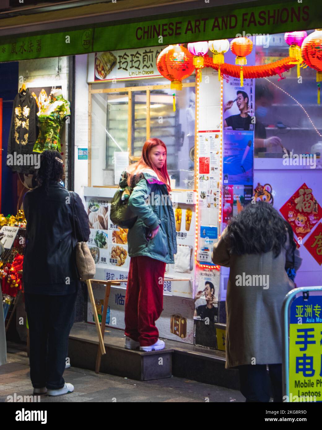 An East Asian woman waiting a kiosk in china town, soho, London. Stock Photo