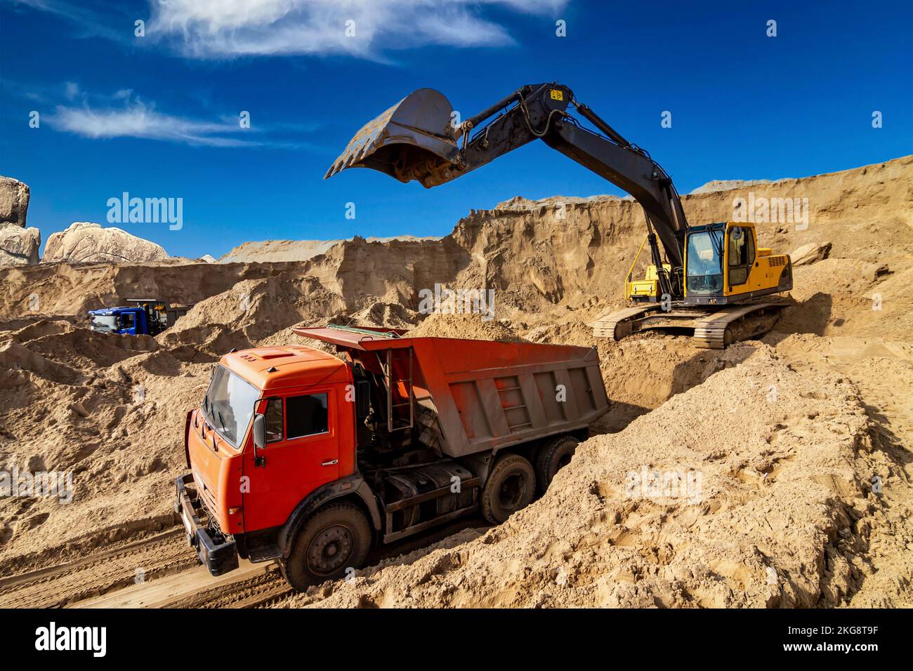 Yellow excavator working with sand at construction site in sunny day ...