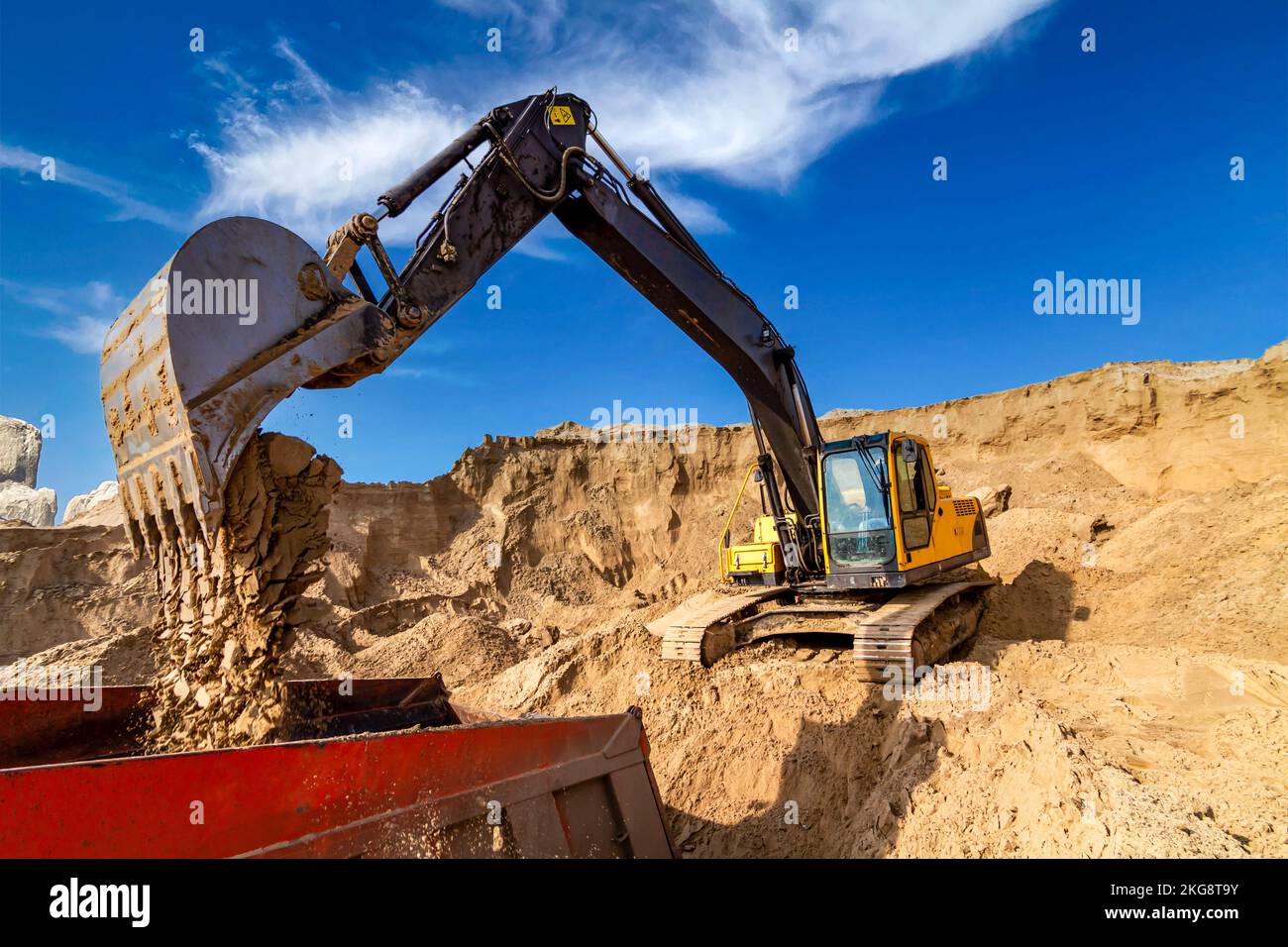Yellow excavator working with sand at construction site in sunny day ...