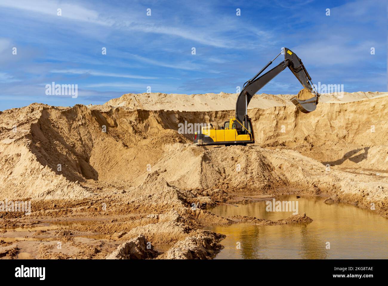 Yellow excavator working with sand at construction site in sunny day ...