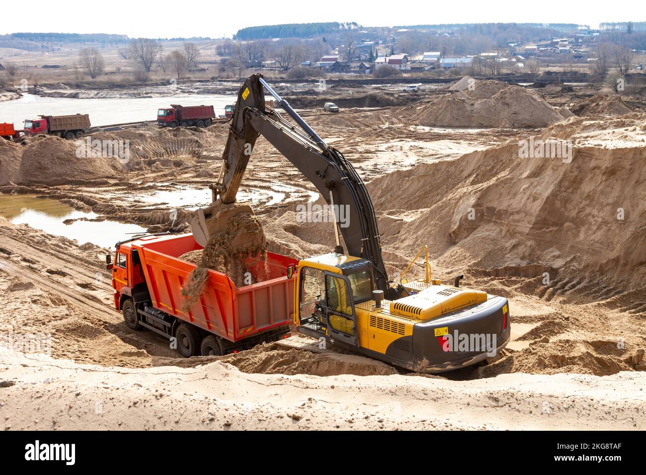 Yellow excavator working with sand at construction site in sunny day ...