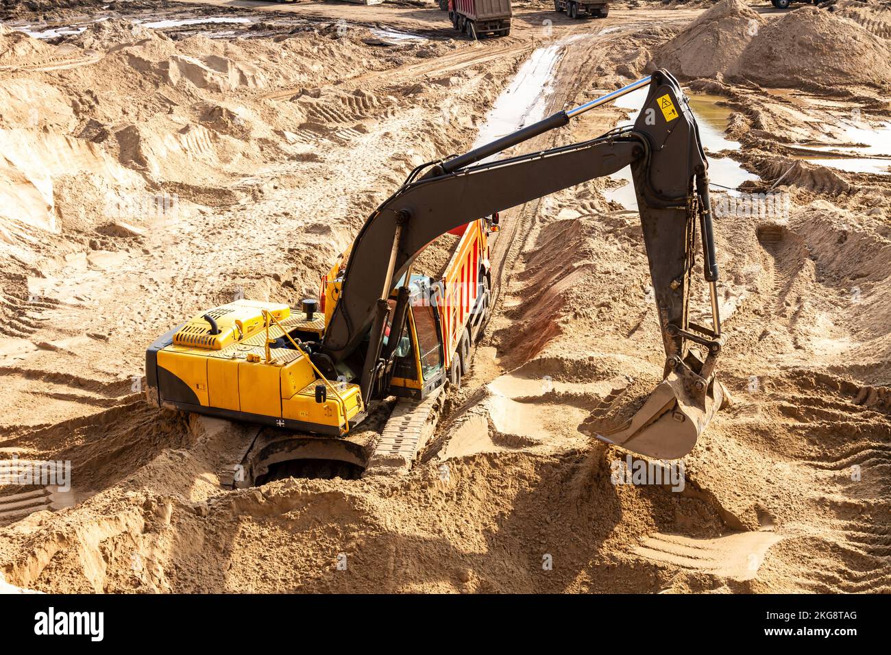 Yellow excavator working with sand at construction site in sunny day ...