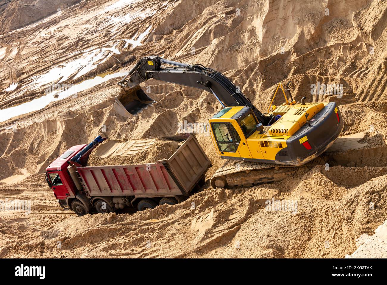 Yellow excavator working with sand at construction site in sunny day ...