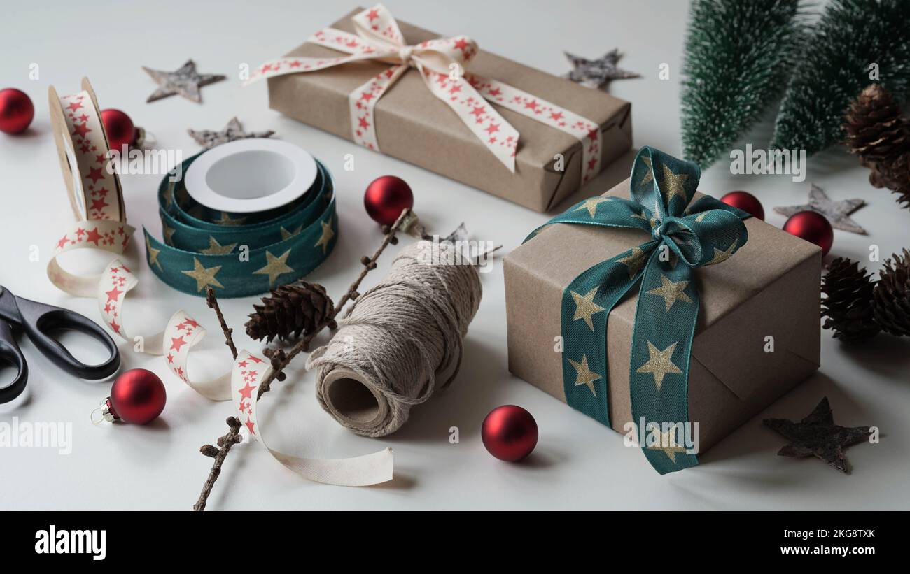https://c8.alamy.com/comp/2KG8TXK/gift-boxes-tied-with-beautiful-ribbons-with-pattern-stars-with-bowrolls-wrapping-paperribbonsropescissorsconesred-balls-white-backgroundprepari-2KG8TXK.jpg