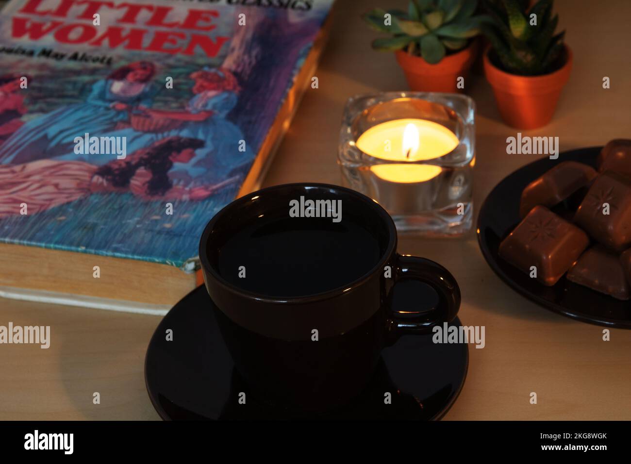 photo cup with a book of little women, a candle and chocolate Stock Photo