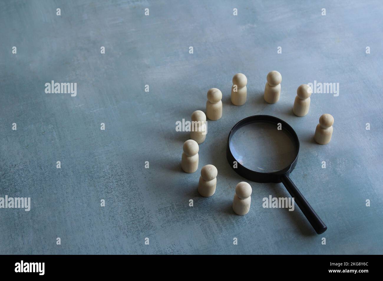 Wooden dolls and magnifying glass. Brainstorm, meeting, investigate, looking for solution concept Stock Photo