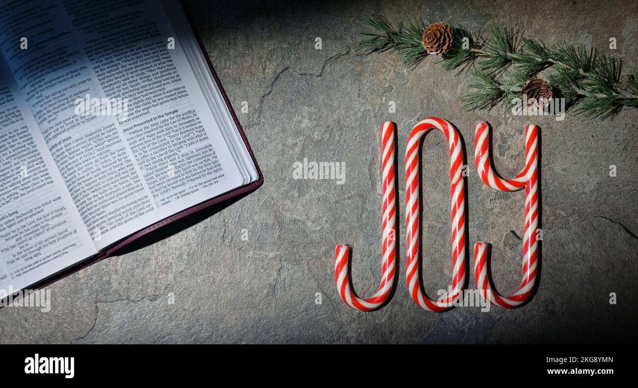 Open Bible and Joy Written With Candy Canes On Stone Table Stock Photo