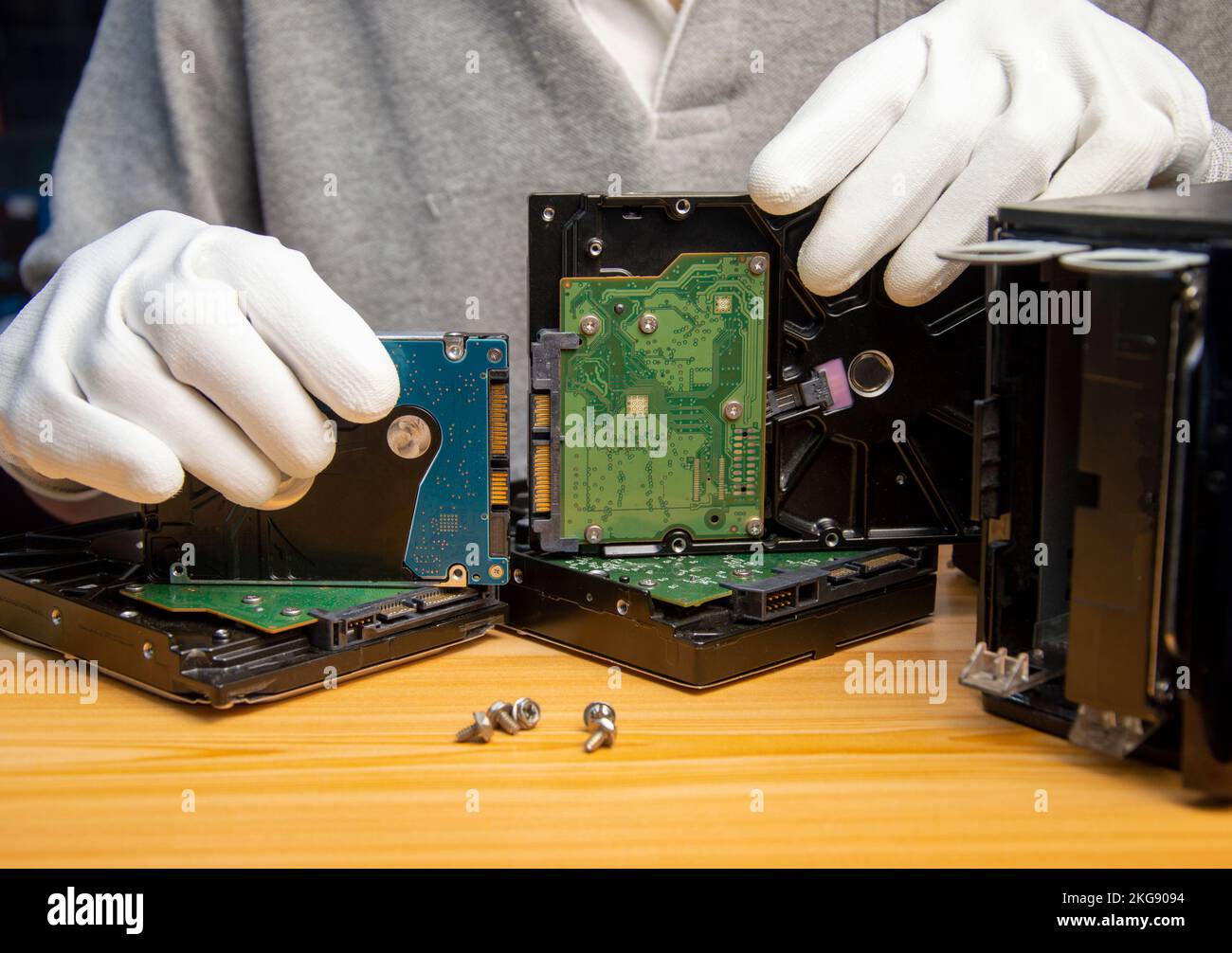 Rotating hard drives are still popular in use today, the technician is holding a hard drive in hand. Stock Photo
