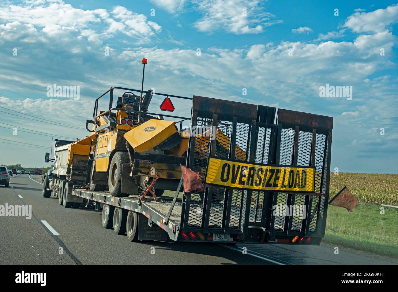 Heavy duty truck pulling a flatbed trailer hauling a Etnyre chip spreader machine used in the road building industry. Minneapolis Minnesota MN USA Stock Photo